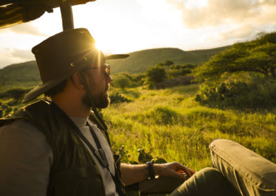 Young Man In Safari Jeep On Game Drive Looking Out At East Afric