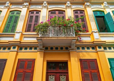 Facade Of French Colonial Style And A Balcony With Flowers And Windows, Hanoi City, North Vietnam.
