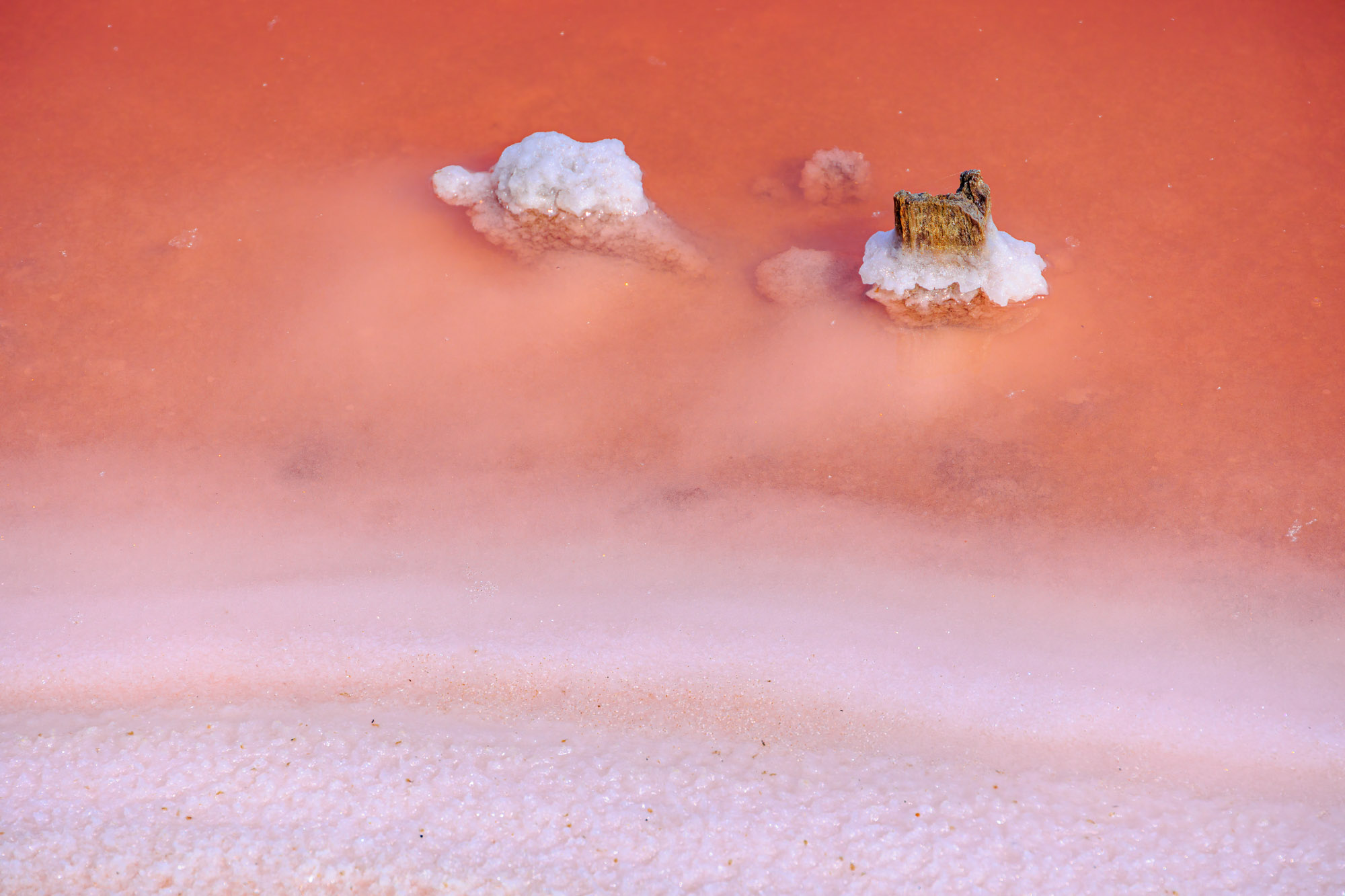 Salt Encrusted Stones And Pink Water In The Salt Flats Near Aigu