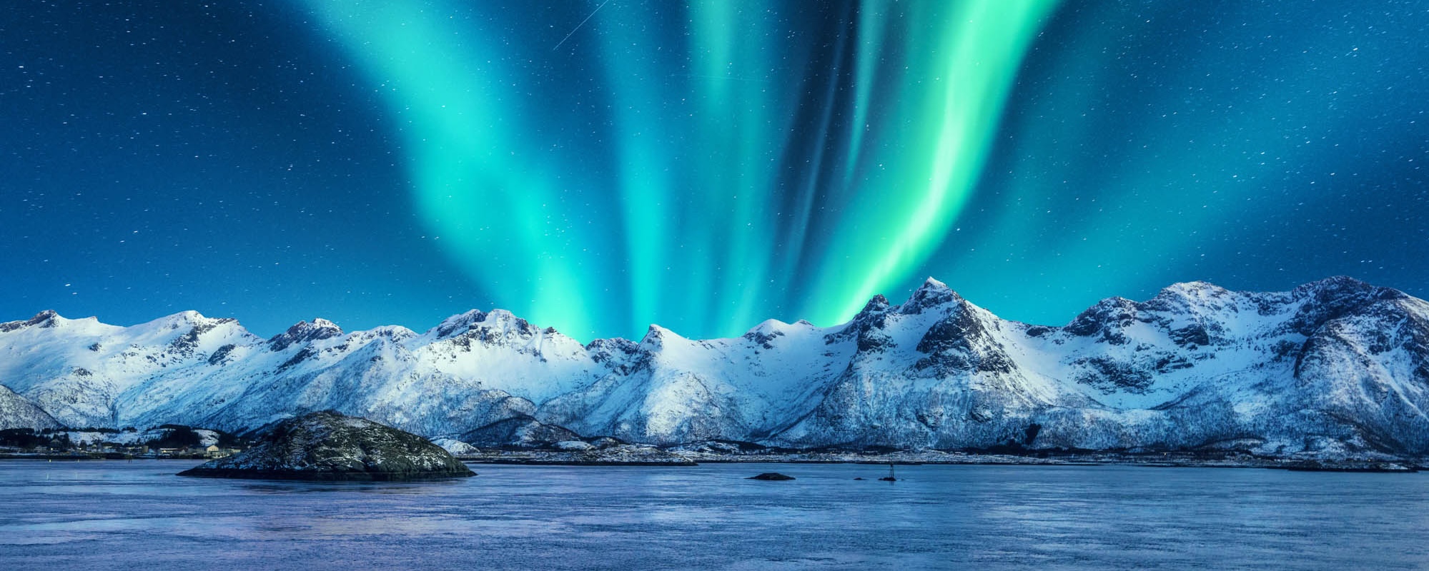 Aurora Borealis Above The Snow Covered Mountains In Lofoten Islands, Norway. Northern Lights In Winter. Night Landscape With Polar Lights, Snowy Rocks, Reflection In The Sea. Starry Sky With Aurora