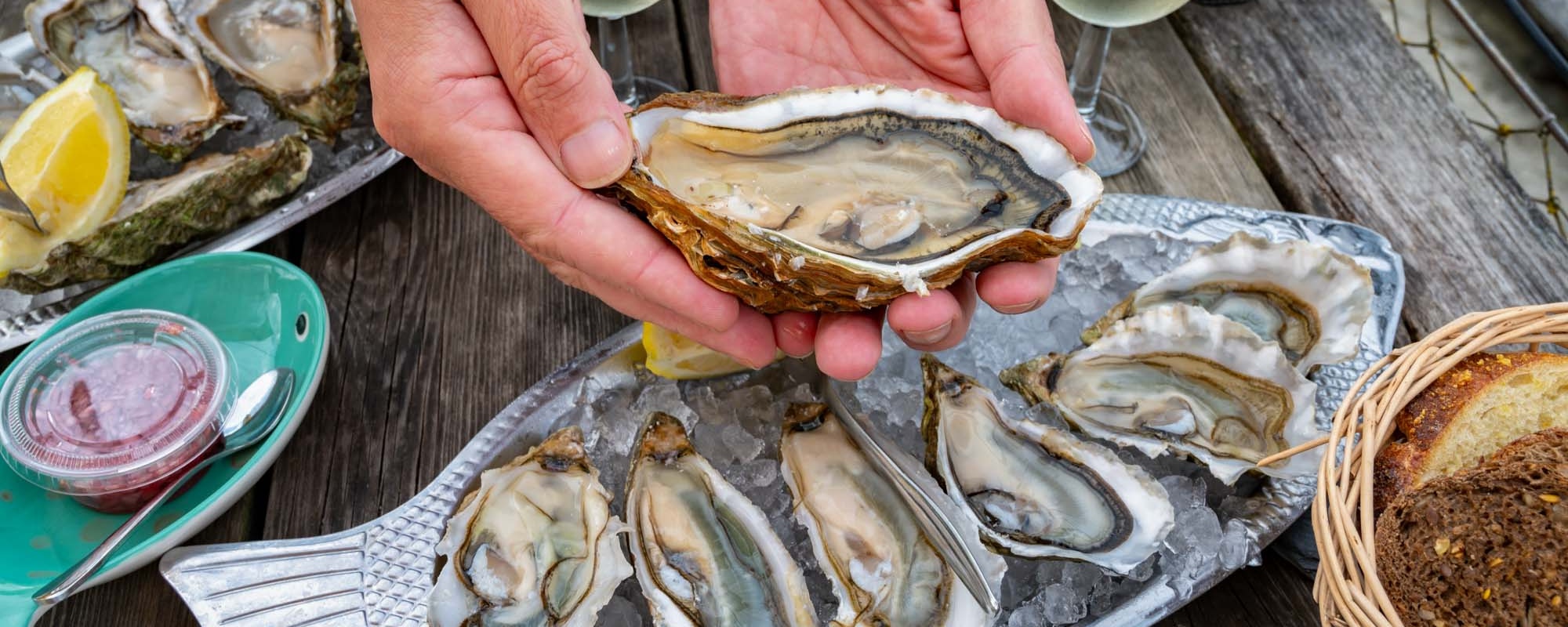 Eating Of Fresh Live Oysters With Citron At Farm Cafe In Oyster Farming Village, Arcachon Bay, Gujan Mestras Port, Bordeaux, France In Sunny Day, Huge Oyster