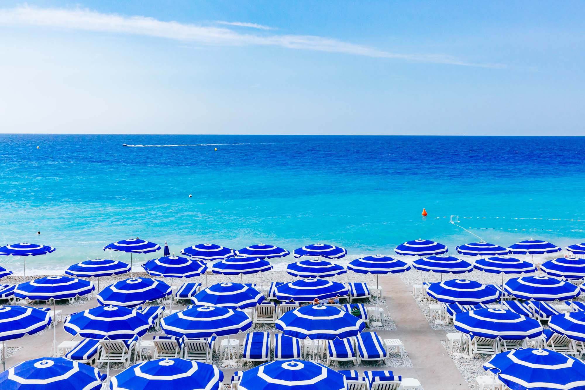 Blue Umbrellas And Chairs On Beach By Blue Sea, In Nice, France Blue Umbrellas And Chairs On Beach By Blue Sea, In Nice, France