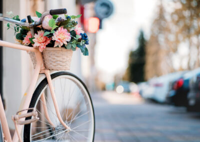 White Bicycle With Basket Of Flowers Standing Near The Door On T