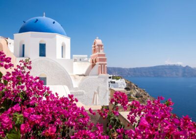 Scenic View Of Traditional Cycladic Houses With Flowers In Foreg